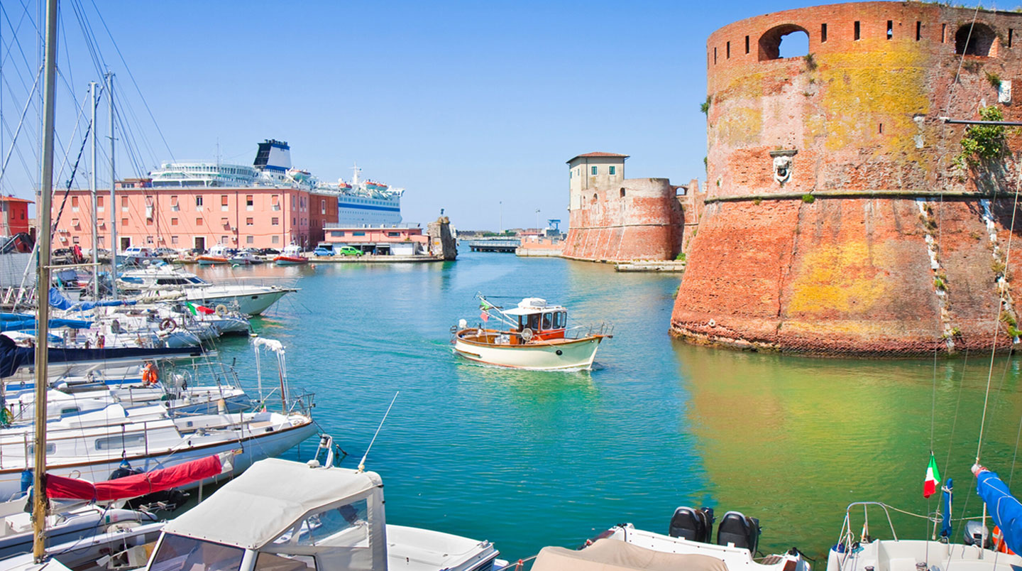 Weitwinklige Aufnahme eines modernen mediterranen Fährhafens mit weissem Fährschiff im Hintergrund, klarem blauen Himmel und zeitgenössischer Infrastruktur